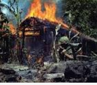 US soldier uses a flame thrower to torch a Vietnamese peasant hut
